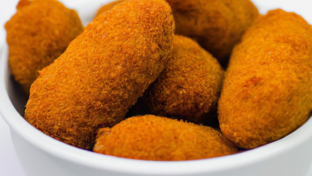 Imagem de croquetes de carne dourados e crocantes servidos em um prato, preparados na Air Fryer. Os croquetes são recheados com carne moída temperada e cobertos com farinha de rosca, criando uma crosta crocante e saborosa.