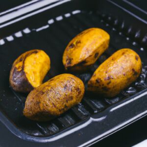 Imagem de uma banana cortada longitudinalmente e colocada em uma fritadeira. A casca da banana está ligeiramente dourada e há uma fatia de banana saliente da fritadeira.