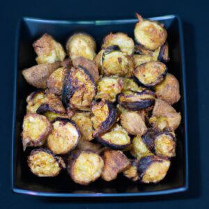 Foto de dadinhos de berinjela fritos em uma airfryer. Os dadinhos são dourados e crocantes, parecidos com pipoca.