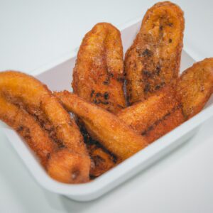 Imagem de bananas fatiadas em rodelas em uma Airfryer. As bananas estão cobertas com uma camada crocante e dourada. A Airfryer é um eletrodoméstico de cozinha que circula ar quente para cozinhar alimentos de forma rápida e uniforme.