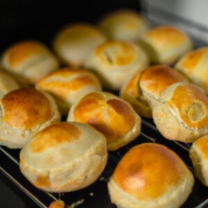 Imagem de uma esfiha fechada feita na airfryer, com uma crosta dourada e recheio suculento visível. A esfiha é colocada em uma superfície escura, com um fundo borrado, destacando a crocância da crosta e o recheio derretido.