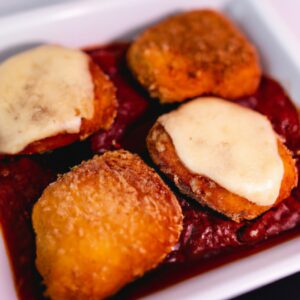 Filé de frango empanado e frito à milanesa, coberto com molho de tomate e queijo, gratinado na Airfryer. A imagem mostra o filé em um prato, com uma fatia de limão ao lado.