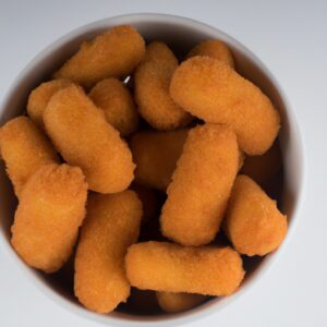 Imagem de uma fogazza frita na airfryer. A fogazza é uma massa frita italiana feita com farinha, água, sal e fermento. É tradicionalmente frita em óleo, mas esta receita usa uma airfryer para obter uma textura crocante e dourada com menos gordura. A fogazza é servida quente com uma variedade de acompanhamentos, como queijo, presunto e tomate.