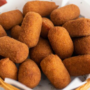 Imagem de quibes fritos na Airfryer, crocantes e dourados, servidos em um prato com rodelas de limão e uma tigela de tahine ao lado.