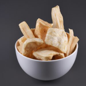 Imagem de mandioca frita na airfryer, com exterior crocante e dourado e interior macio e branco. Os palitos de mandioca são dispostos em uma cesta de airfryer, com um pouco de sal e pimenta polvilhados por cima.