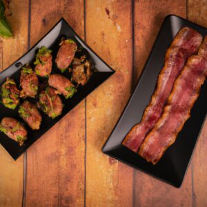 Duas medalhas de carne suculentas, uma coberta com bacon crocante e a outra com abobrinhas douradas, grelhadas à perfeição em uma Airfryer. O bacon fica salgado e adiciona um toque crocante, enquanto a abobrinha oferece uma doçura leve e um toque refrescante. As medalhas são grelhadas até ficarem cozidas, mantendo sua suculência e maciez.