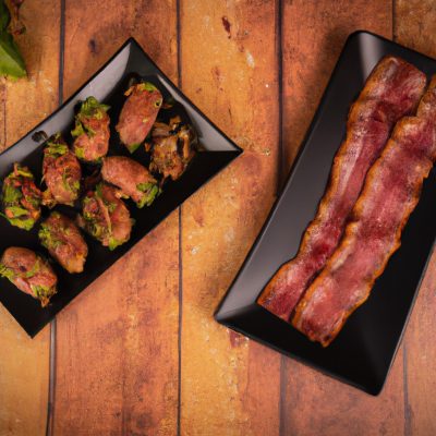 Duas medalhas de carne suculentas, uma coberta com bacon crocante e a outra com abobrinhas douradas, grelhadas à perfeição em uma Airfryer. O bacon fica salgado e adiciona um toque crocante, enquanto a abobrinha oferece uma doçura leve e um toque refrescante. As medalhas são grelhadas até ficarem cozidas, mantendo sua suculência e maciez.