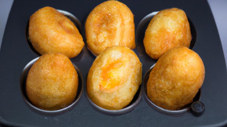 Imagem de um ovo frito cozido em uma airfryer. O ovo tem uma gema amarela brilhante e uma clara branca cozida, cercada por uma borda crocante e dourada. A cesta da airfryer é visível ao fundo.