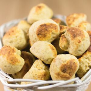Imagem de pãezinhos de aveia dourados e fofos recém-saídos de uma Airfryer. Os pãezinhos estão em uma cesta forrada com papel manteiga e têm um leve tom marrom.