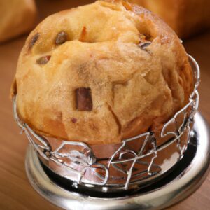 Imagem de um panetone salgado dourado e crocante assado em uma Airfryer, com queijo derretido escorrendo pelas laterais. O panetone é guarnecido com ervas frescas e fatias de tomate para um toque extra de sabor.