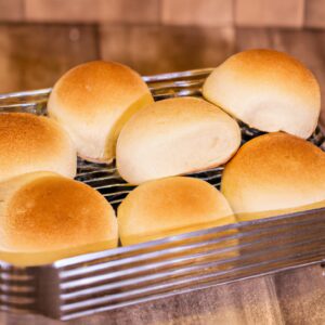 Imagem de uma cesta de airfryer cheia de fatias de pão fresco recém-assado. As fatias são douradas e crocantes nas bordas, e macias e fofas no interior. O pão é branco ou integral, e pode ser tradicional ou sem glúten e sem lactose, dependendo da preferência.