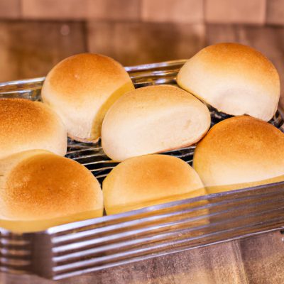 Imagem de uma cesta de airfryer cheia de fatias de pão fresco recém-assado. As fatias são douradas e crocantes nas bordas, e macias e fofas no interior. O pão é branco ou integral, e pode ser tradicional ou sem glúten e sem lactose, dependendo da preferência.