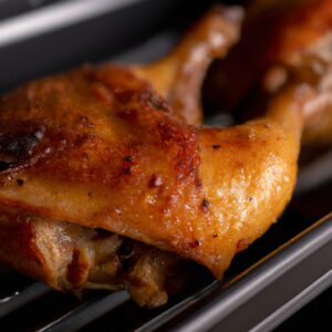 Uma foto de vários peitos de frango assados ​​em uma cesta de fritadeira. Os peitos de frango são dourados e crocantes, com marcas de grelha. Eles são guarnecidos com ervas frescas, como salsa e tomilho.