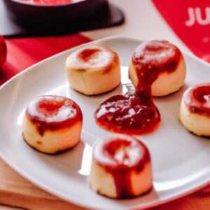 Uma foto de uma airfryer aberta com um petit gateau de queijo com goiabada dentro. O petit gateau tem uma crosta dourada e um centro cremoso. A goiabada está por cima do petit gateau, criando um contraste de cores.