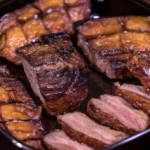 Picanha suculenta e grelhada preparada na Airfryer, mostrando sua superfície externa crocante e interior macio e rosado. A picanha é apresentada em um prato, acompanhada por uma guarnição de legumes grelhados.