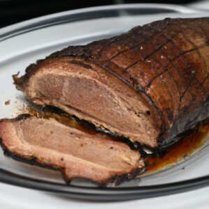 Imagem de uma picanha suína assada na Airfryer. A carne está dourada e suculenta, e é servida com uma salada de folhas verdes e um molho à parte.