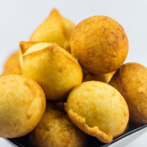 Imagem de uma assadeira com polpetones recheados cozidos na Air Fryer. Os polpetones são dourados e crocantes, com recheio de queijo derretido visível. Eles estão dispostos em uma camada única na assadeira, com espaço entre eles para permitir a circulação de ar.