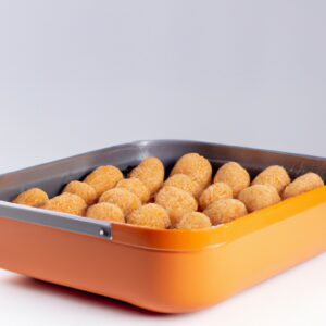 Imagem de um quibe frito e dourado em uma airfryer. O quibe é feito com carne moída, trigo bulgur e especiarias. Ele é moldado em uma forma oval e frito até ficar crocante.