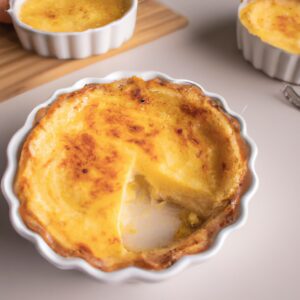 Imagem de uma quiche integral de alho-poró cozida em uma airfryer. A quiche está em uma forma de torta redonda e tem uma crosta dourada. O recheio é verde escuro e contém alho-poró, ovos e queijo.