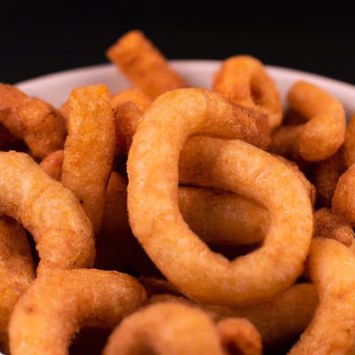 Imagem de uma porção de rabanada salgada crocante cozida em uma Airfryer. As rabanadas são douradas e cobertas com uma mistura de queijo parmesão e ervas, e são servidas com um molho de tomate à parte.