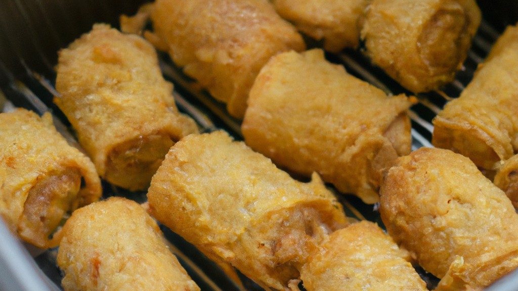 Imagem de um prato de rocambole de frango feito na Airfryer. O prato mostra um rocambole cortado em fatias, com recheio de espinafre e queijo derretido visível. A crosta externa do rocambole é dourada e crocante, e é guarnecida com tomate cereja e manjericão.