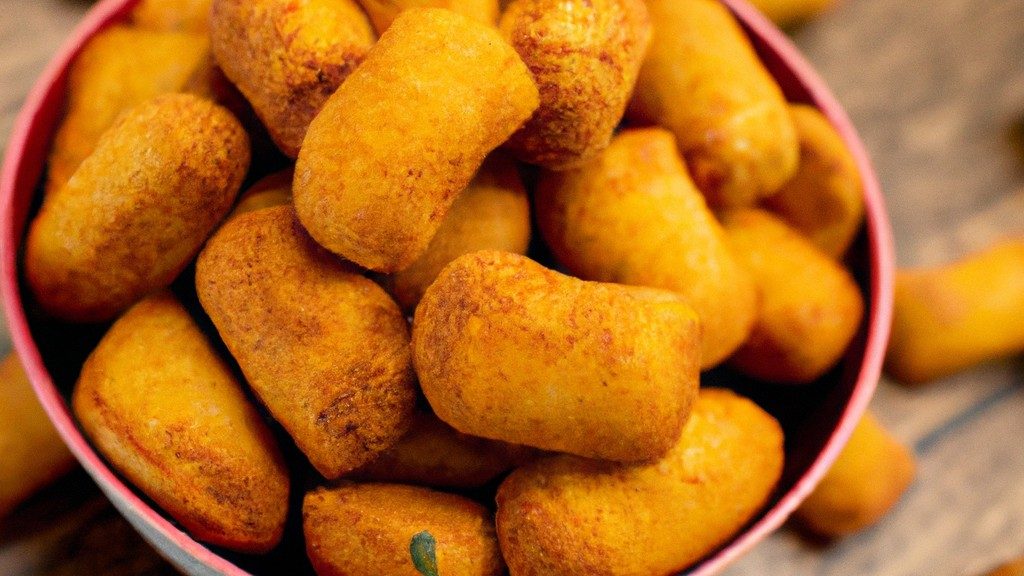 Imagem de uma Airfryer com uma cesta cheia de comida cozida, como batatas fritas, nuggets de frango e vegetais. O texto 