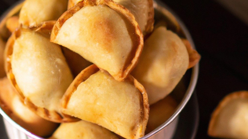 Imagem de trouxinhas de massa de pastel recheadas com arroz, carne suína e fritas em uma Airfryer.