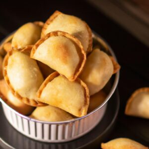 Imagem de trouxinhas de massa de pastel recheadas com arroz, carne suína e fritas em uma Airfryer.