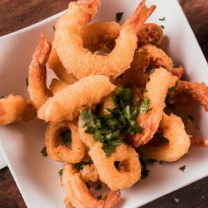 Imagem de camarões crocantes e dourados cozidos em uma airfryer. Os camarões são temperados com ervas e especiarias e têm um aspecto delicioso e apetitoso.