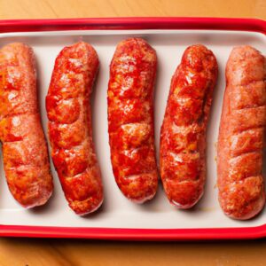 Imagem de salsichas italianas cozidas em uma Airfryer. As salsichas são douradas e crocantes, e estão dispostas em um prato branco.